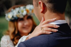 Loving bride in wedding ring embracing crop groom and smiling happily at romantic ceremony in park